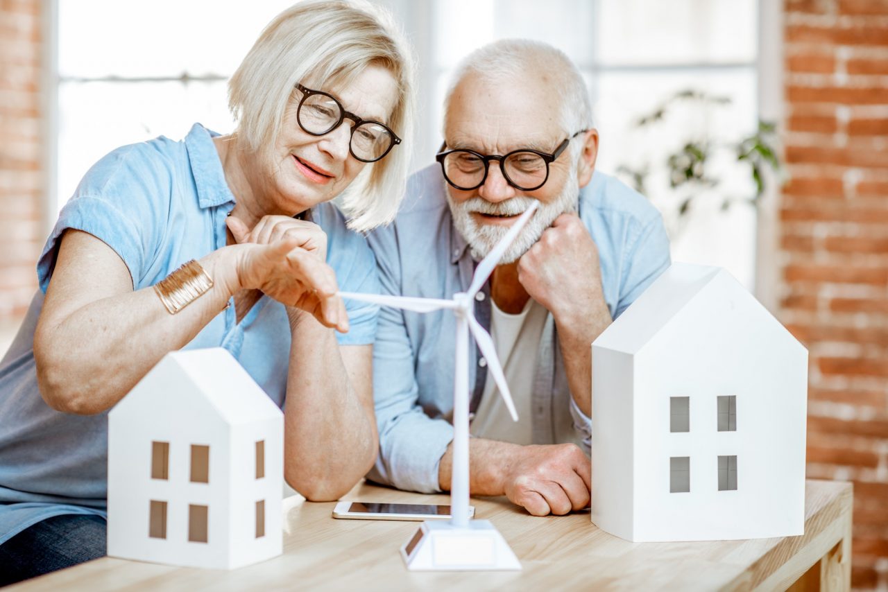 Senior couple with house models and toy wind turbine at home